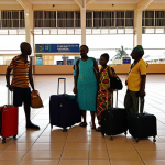 **Image Prompt 1: First Arrival at Yaoundé Nsimalen Airport**
    A wide shot capturing the arrival hall of Yaoundé Nsimalen International Airport, bathed in warm, humid light. Travelers of diverse backgrounds, some looking slightly tentative, others relaxed locals, stand in immigration lines or collect luggage. The atmosphere is a mix of quiet anticipation and subtle African vibrancy. Through large windows, a hint of the runway or tropical foliage can be seen. The setting feels authentic and slightly aged, not overly modern.